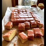 Fresh lemon bars with a glossy glaze on parchment paper.
