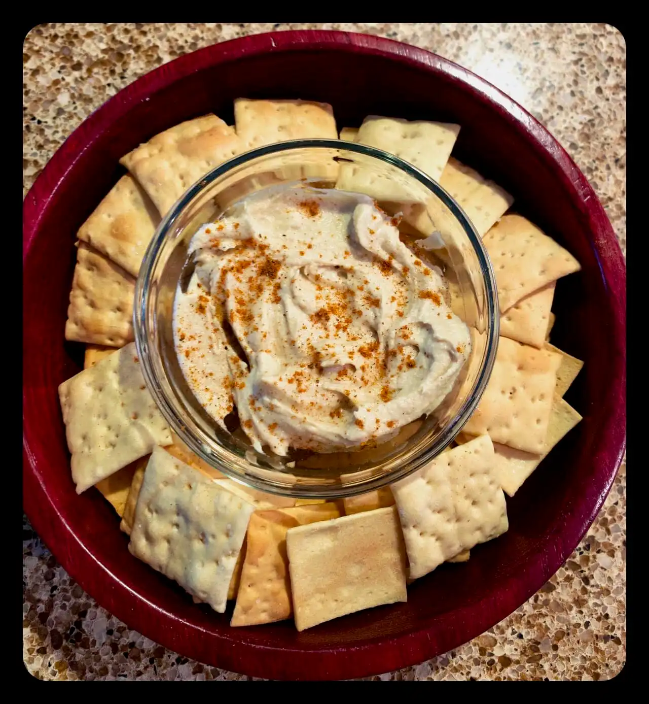 Cheese and crackers with dip on a red platter, perfect for snacking.